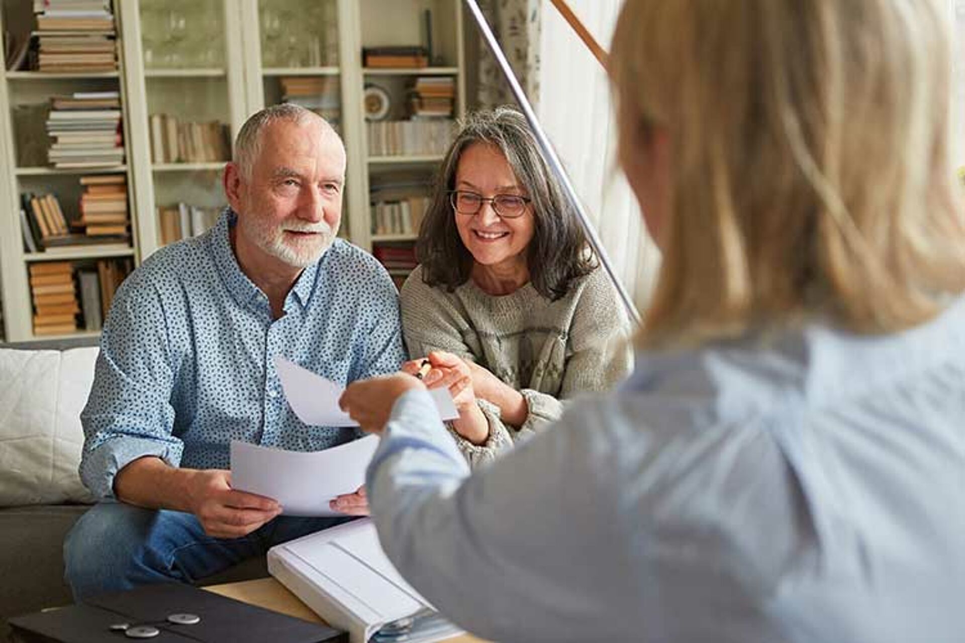 Pflegeberatung zu Hause: Beratungsgespräch mit einem älteren Paar im Wohnzimmer